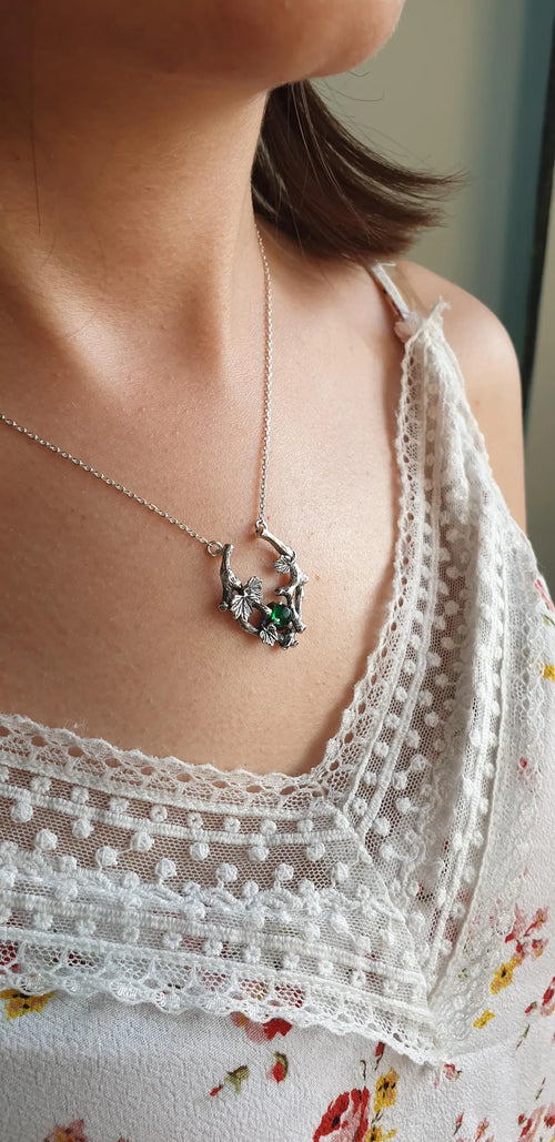 Grape vine necklace with green stone worn with a white lace top