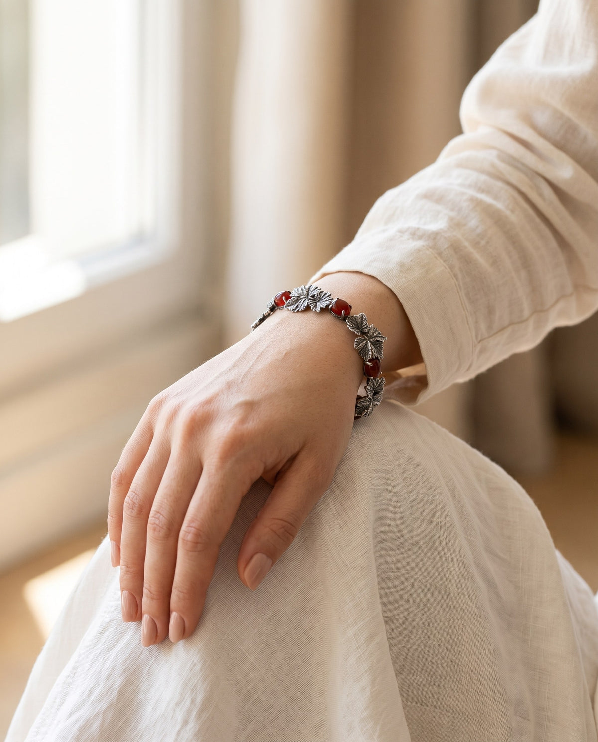 Silver grape vine bracelet with red carnelians worn on a woman's wrist