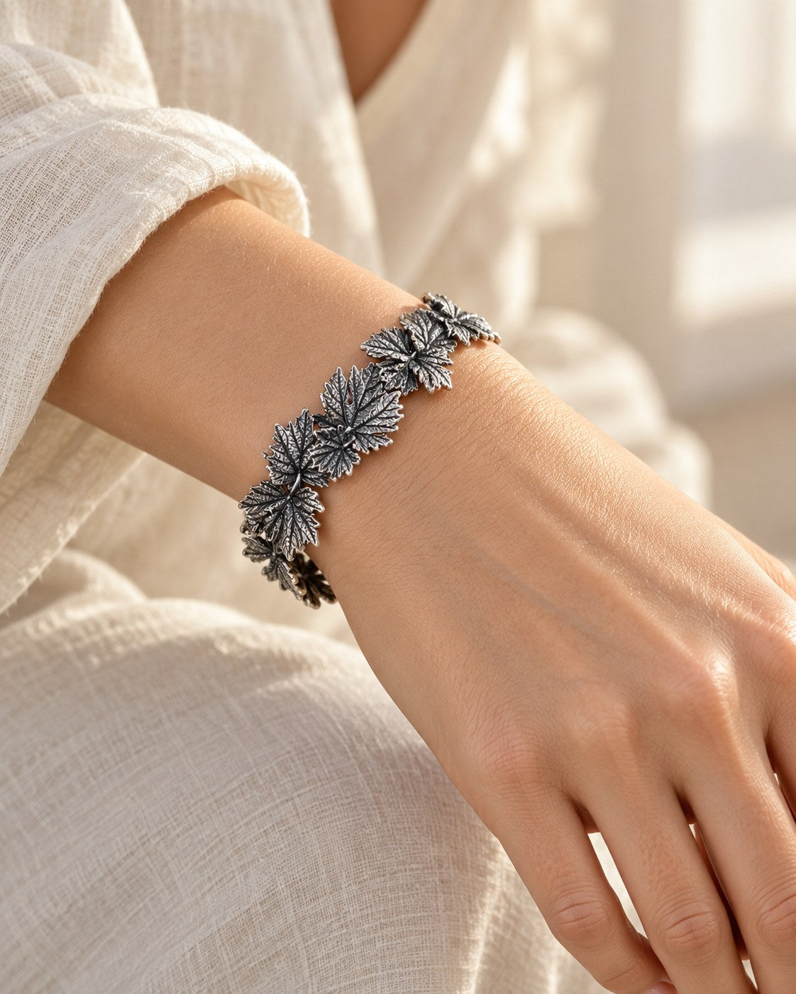 Silver grape leaf garland bracelet worn on a woman's wrist