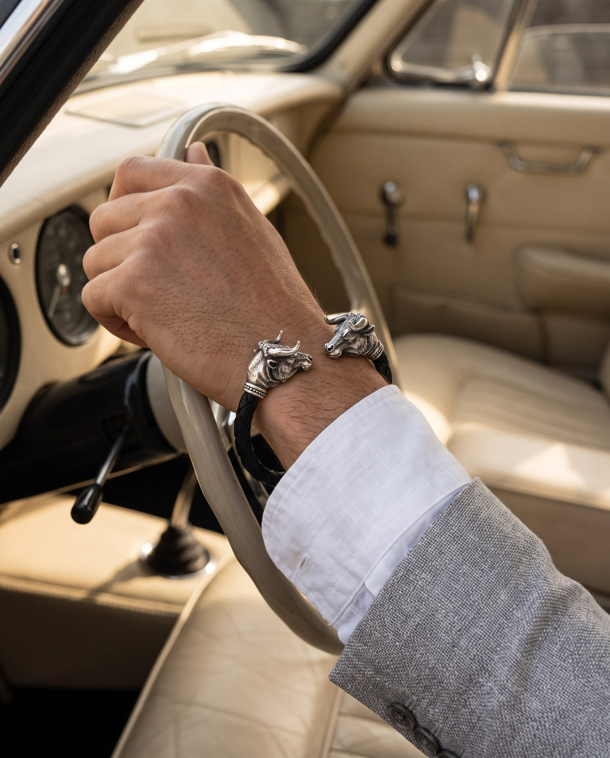 Braided black leather bracelet with two silver bull heads worn on a man's wrist