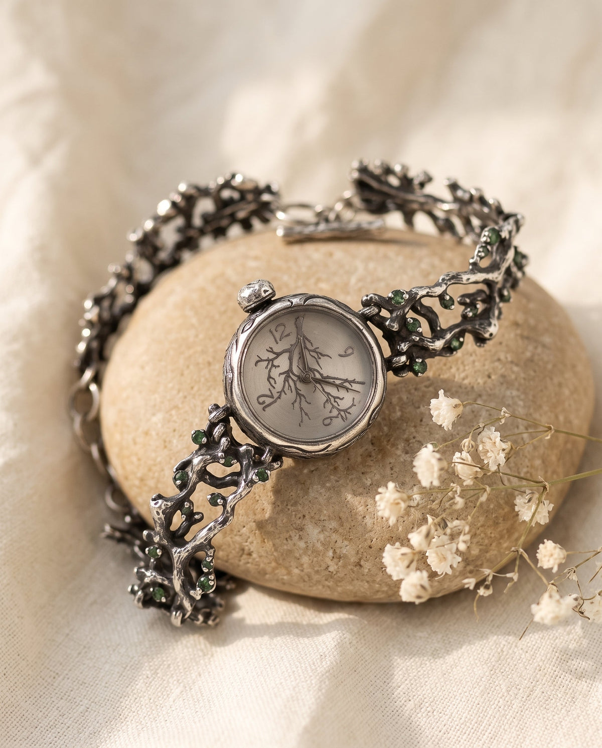 Aurelliani vine watch, sterling silver vine bracelet with green stones, on a river stone
