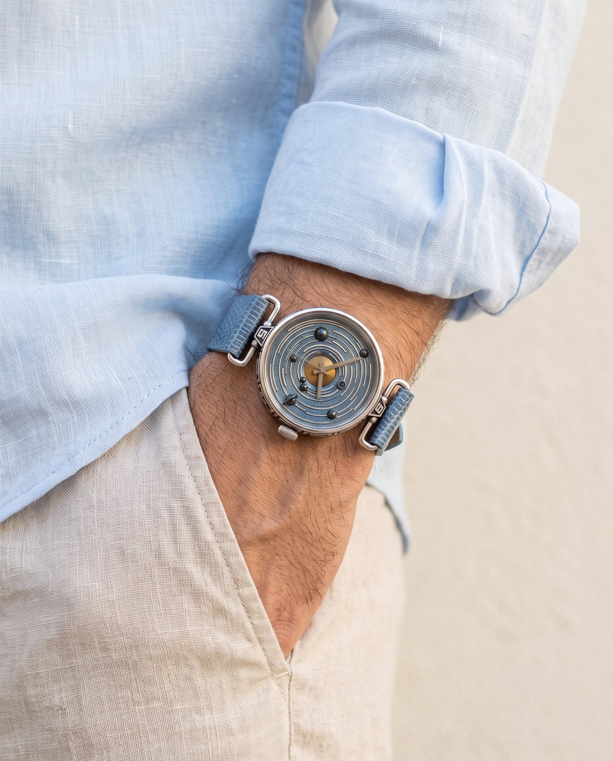 Aurelliani solar system watch with blue lizard strap worn on a man's wrist