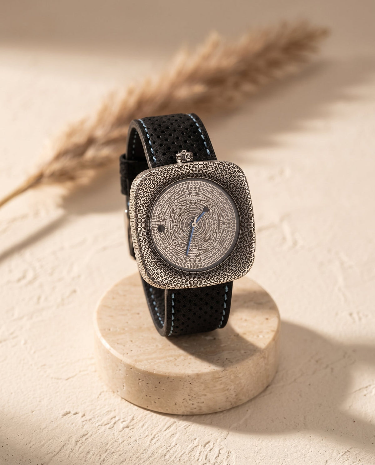Aurelliani engraved cushion-case silver watch with black perforated strap on travertine