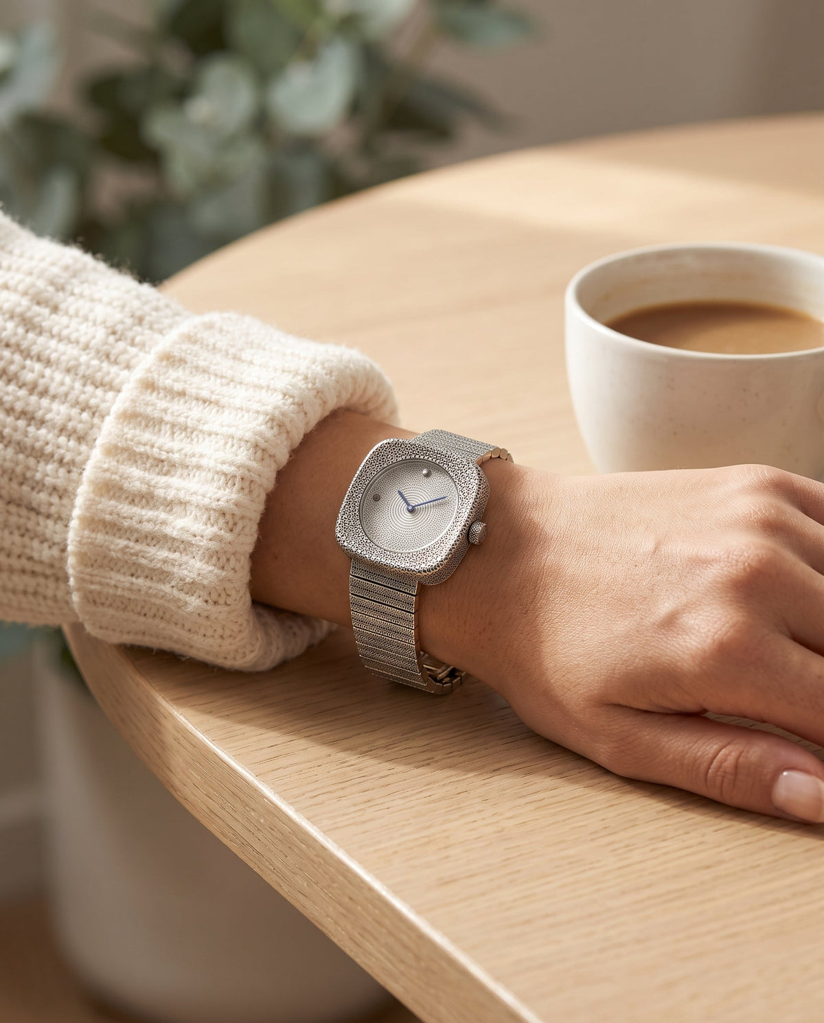 Aurelliani engraved cushion-case silver watch on a silver bracelet worn on a woman's wrist