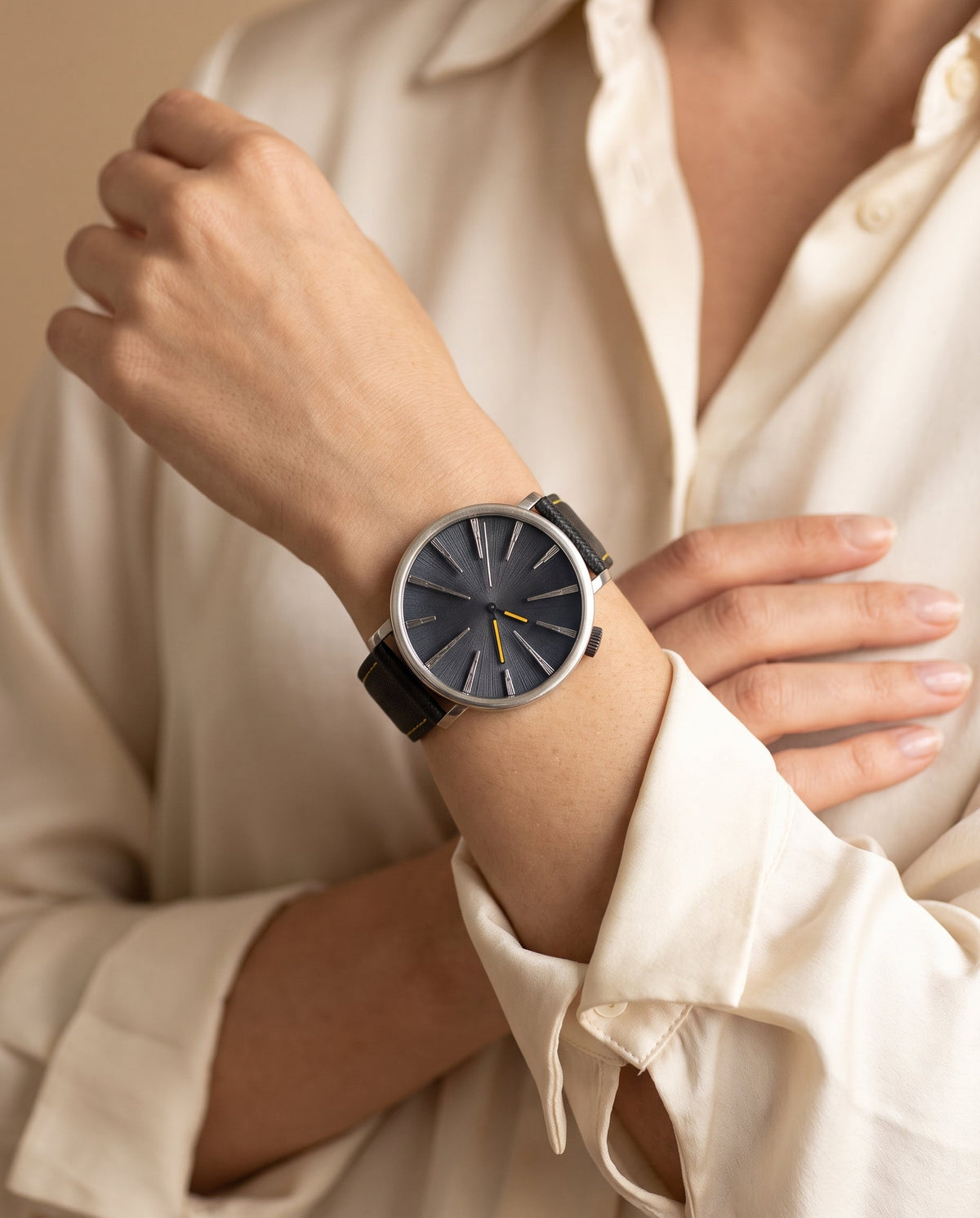 Aurelliani navy radial dial watch with yellow seconds hand worn on a woman's wrist