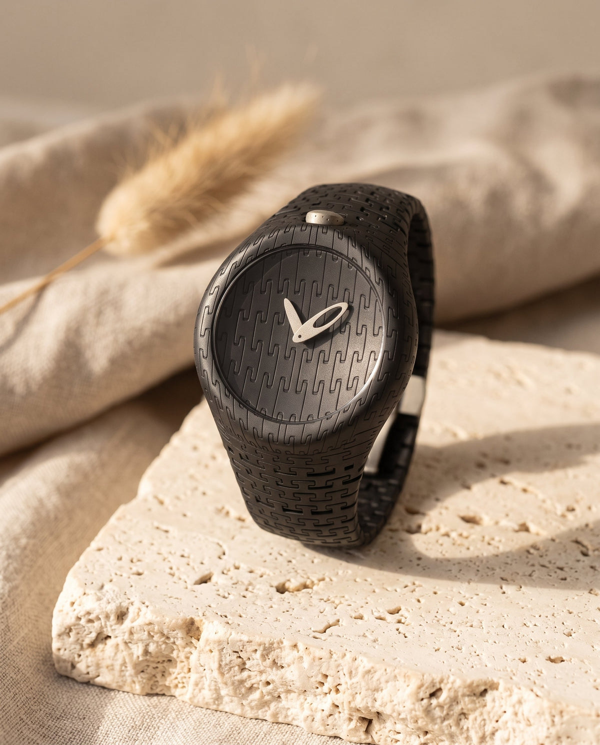 Aurelliani sculpted black watch with silver hands standing on travertine