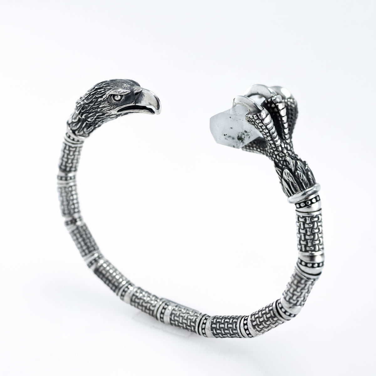Silver eagle cuff with an eagle head on one end and a talon holding raw rock crystal on the other
