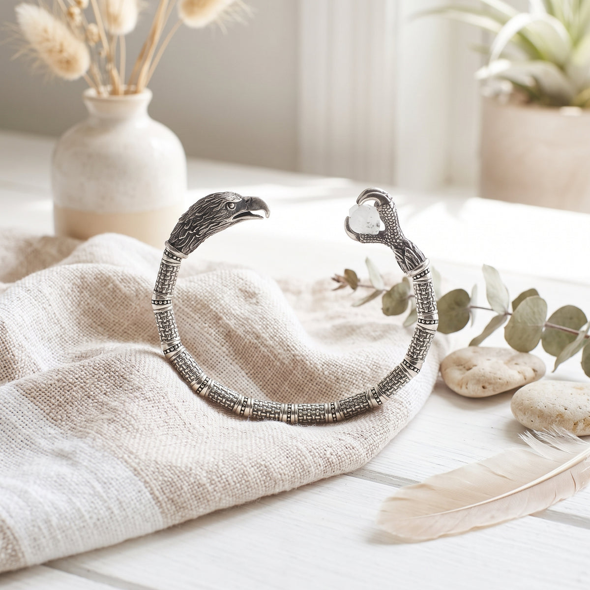 Silver eagle cuff on linen with a feather