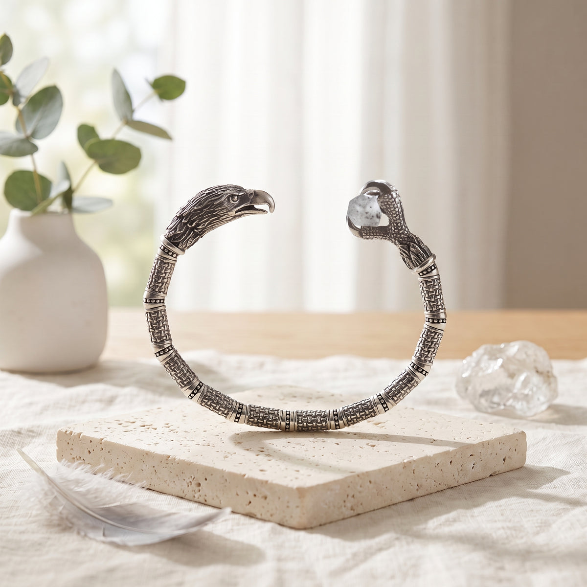Silver eagle cuff on travertine beside raw crystal