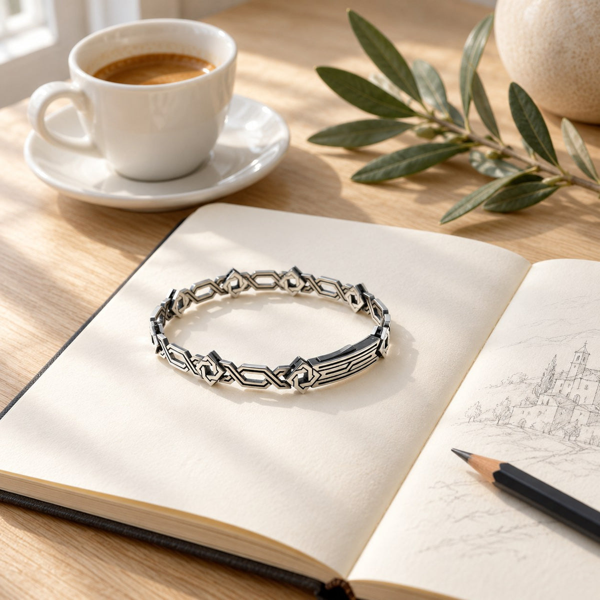 The bracelet on an open notebook beside a cup of coffee