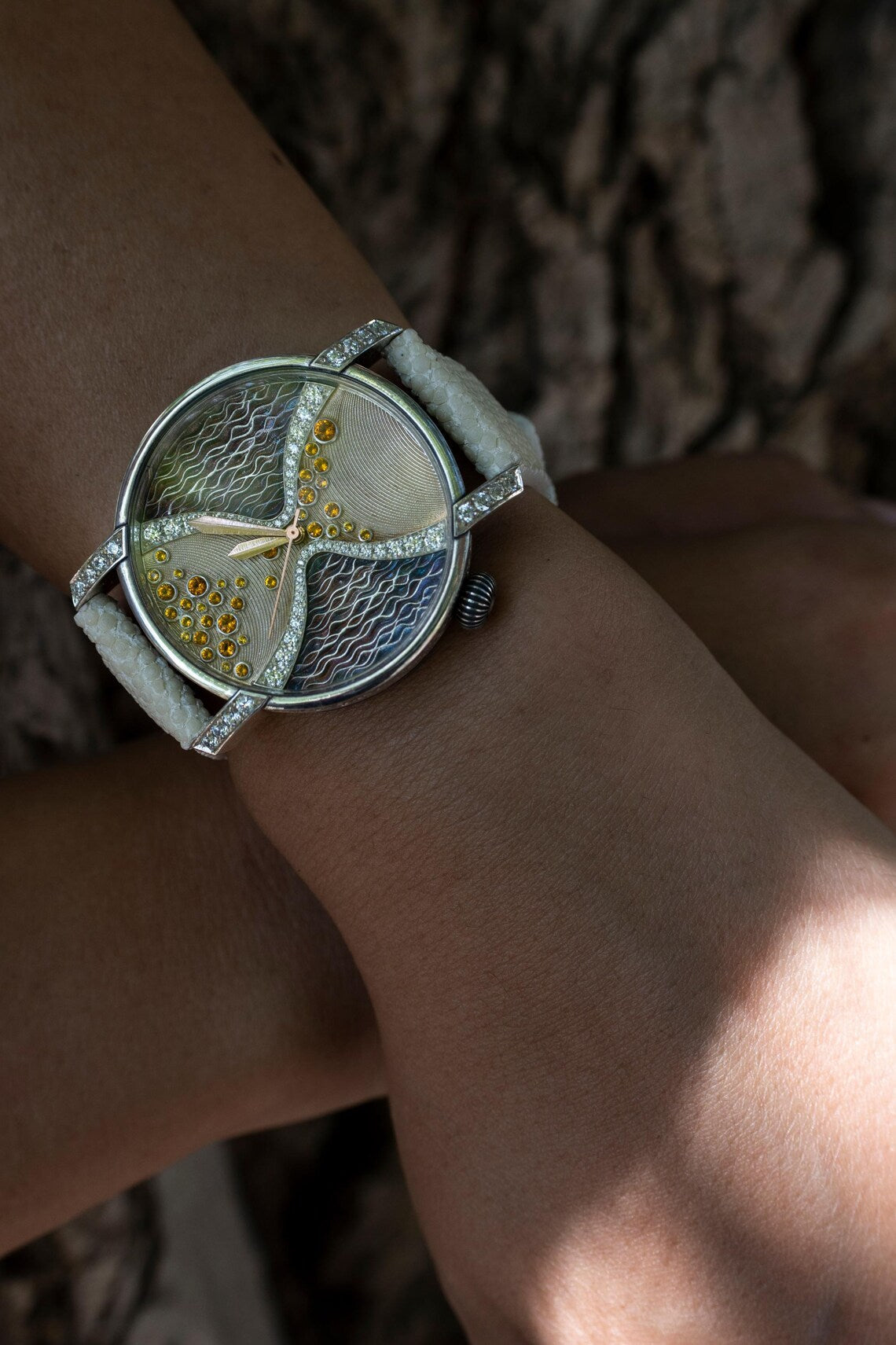 Silver watch with stone set dial worn on the wrist