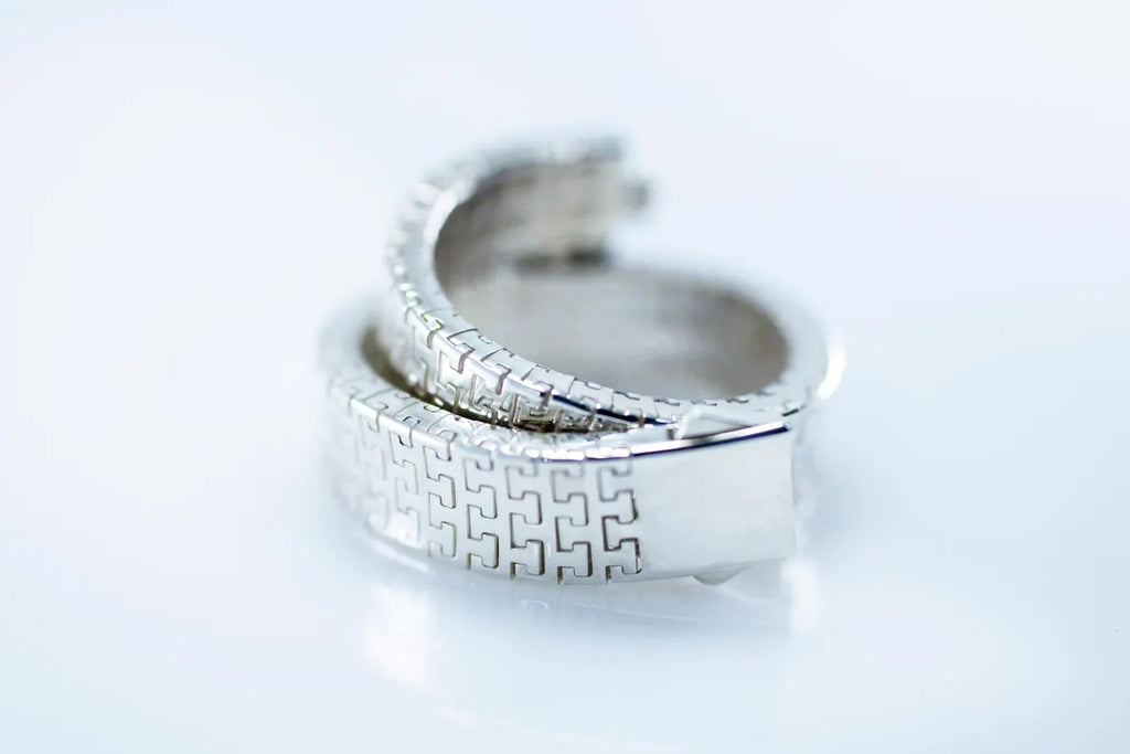 Rhodium-plated woven link bracelet coiled on a pale background