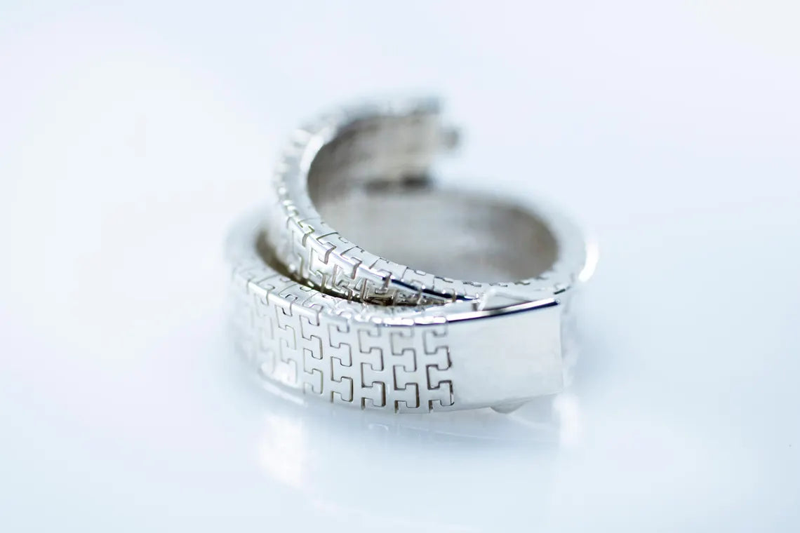 Rhodium-plated woven link bracelet coiled on a pale background