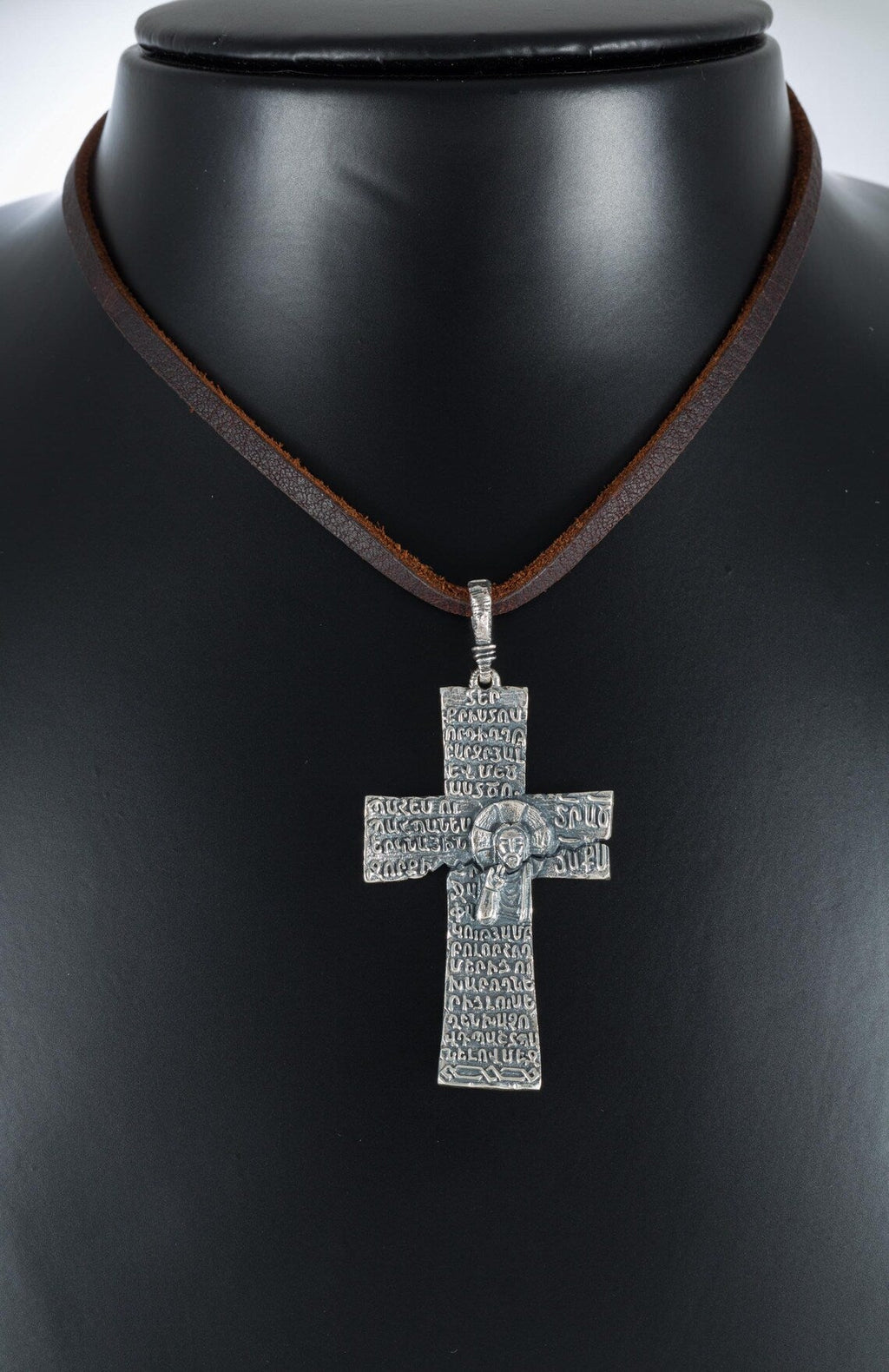 Oxidized silver cross pendant with Armenian letters on a display bust